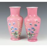 A pair of Victorian painted pink glass vases decorated with flowers 29cm