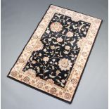A black and gold ground Persian style machine made rug with floral pattern to the centre within a