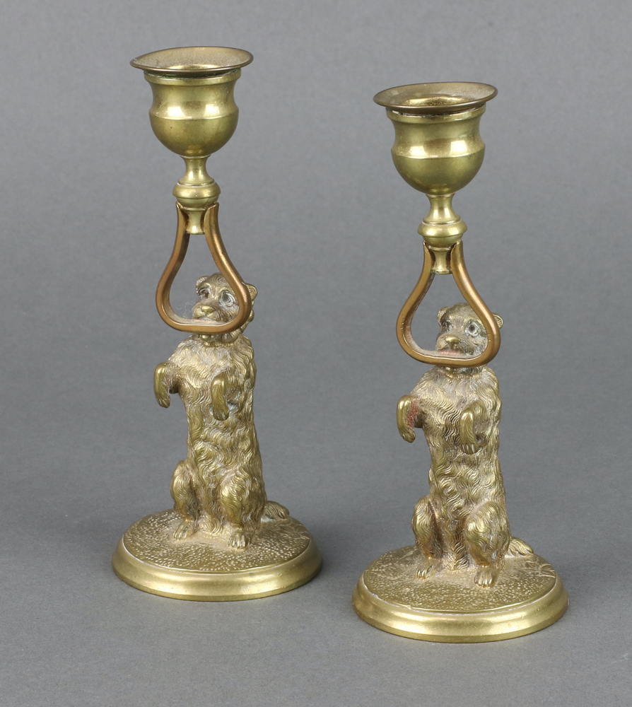 A pair of 19th Century gilt metal candlesticks in the form of standing dogs, raised on circular