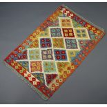 An orange, green, brown and blue ground Chobi Kilim rug with diamond decoration to the centre