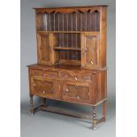 A 1920's Jacobean style oak dresser the raised back with moulded cornice, shelf above recess flanked