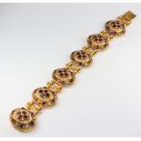 A mid Victorian brass and garnet set 6 plaque bracelet 19cm, the backs are inlaid with mother of
