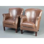 A pair of 1930's style club armchairs upholstered in brown leather material, raised on outswept