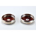 A PAIR OF ELIZABETH II CIRCULAR SILVER DECANTER COASTERS with turned mahogany bases, maker: B & Co,