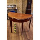 A GEORGE III MAHOGANY HALF ROUND FOLD OVER TOP TEA TABLE, boxwood strung frieze,