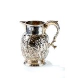 A LARGE LATE VICTORIAN SILVER JUG with embossed foliate and scroll decoration and leaf capped