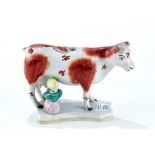 A 19th CENTURY STAFFORDSHIRE POTTERY COW CREAMER, with seated milk maid on a shaped base,