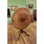 A GEORGE III CIRCULAR MAHOGANY TILT TOP TRIPOD TABLE raised on a baluster turned column and