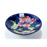 A WILLIAM MOORCROFT BLUE GROUND BOWL, decorated with hibiscus, impressed marks & WM script,