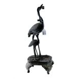 AN ORIENTAL BRONZE GROUP depicting two storks raised on an elaborate base with four feet,