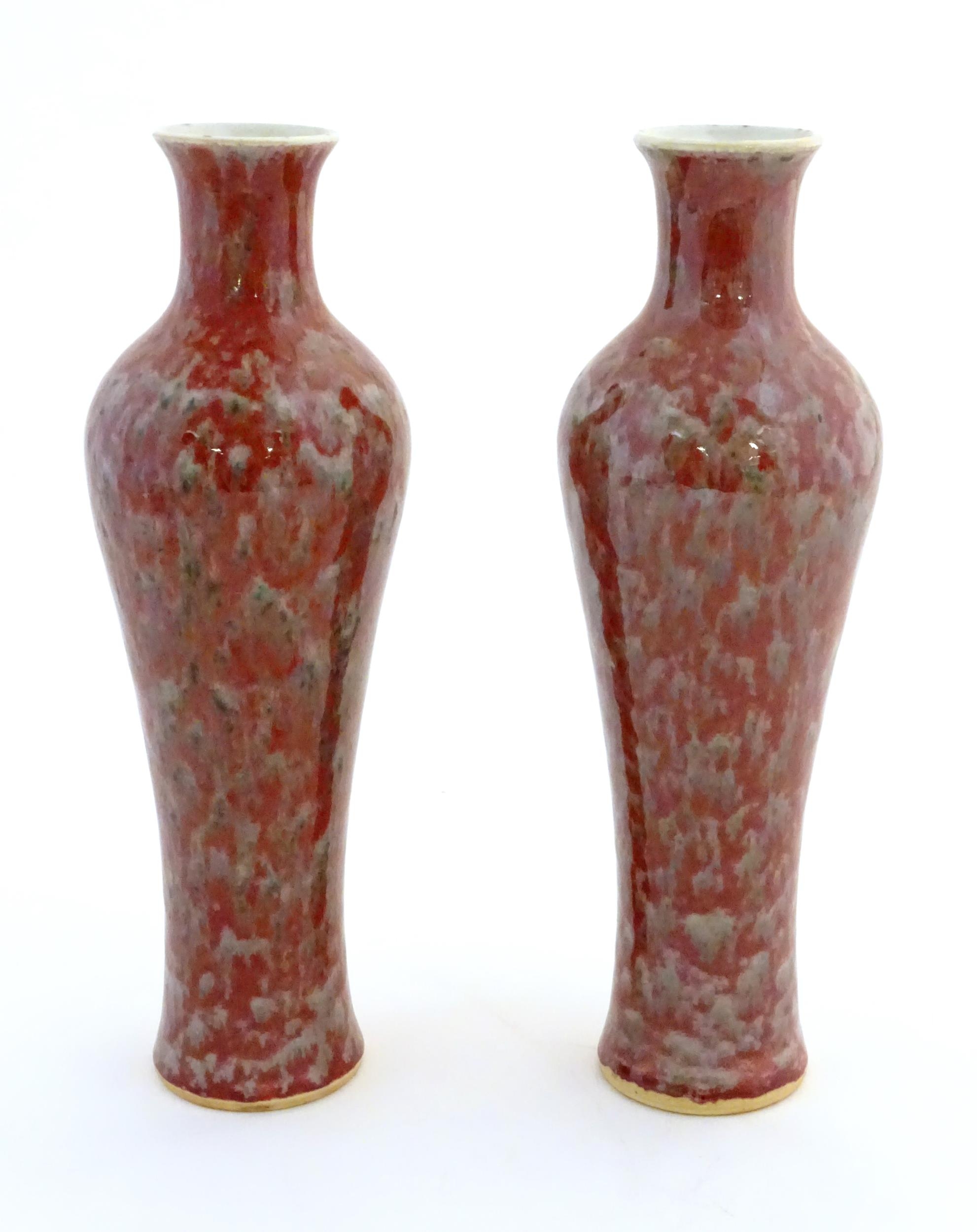 A pair of Chinese vases of elongated form decorated with a mottled glaze. Double ring mark under.
