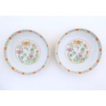 A pair of Chinese plates / dishes with central roundels depicting flowers and a foliate border.