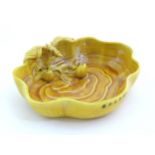 A Chinese fluted edged yellow brush wash dish with relief bat and fruit decoration. Character