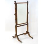 An early / mid 19thC mahogany cheval mirror surmounted by gadrooned finials above two turned