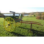 A horse drawn gig / trap / cart in green, red and yellow livery with two wheels and two black