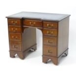 An early / mid 20thC mahogany kneehole desk with a reeded inverted breakfront top above two banks of