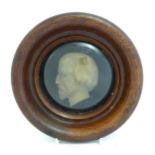 A 20thC cast tondo profile portrait of a bearded gentleman, behind convex glass within a turned