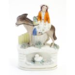 A Staffordshire pottery flat back figure depicting a young lady seated upon a donkey, with a swan