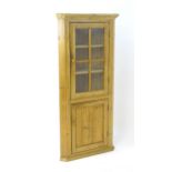 A 19thC pine corner cupboard with a moulded cornice above an astragal glazed door and a panelled