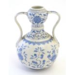 An Oriental blue and white double gourd vase with twin handles decorated with scrolling floral and