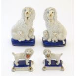 A pair of Staffordshire pottery models of seated Poodle dogs with puppies, together with a pair of