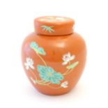 A Chinese ginger jar with an orange ground decorated with flowers and foliage. Character marks