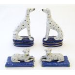 A pair of Staffordshire pottery models of seated Dalmatians dogs on oval bases, together with a pair