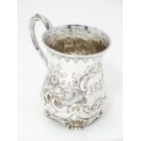 A Victorian silver christening mug with embossed floral and C-scroll decoration. Hallmarked