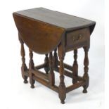 An 18thC oak gateleg table open to form an oval table top above a peg jointed bae and with block and