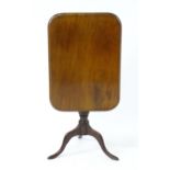 An early 19thC mahogany tilt top table with a moulded rectangular top above a carved pedestal with