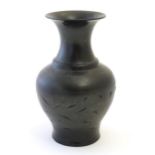 An Oriental black vase of baluster form with a flared rim and incised foliate detail. Approx. 10 1/