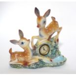 A kitsch novelty clock the timepiece set within a ceramic figure group depicting two deer / fawns.