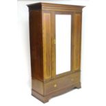 An early 20thC mahogany wardrobe with a moulded cornice above a central mirrored door and a single