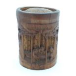 An Oriental bamboo pot and cover with carved detail depicting 3 sage figures in a woodland scene.