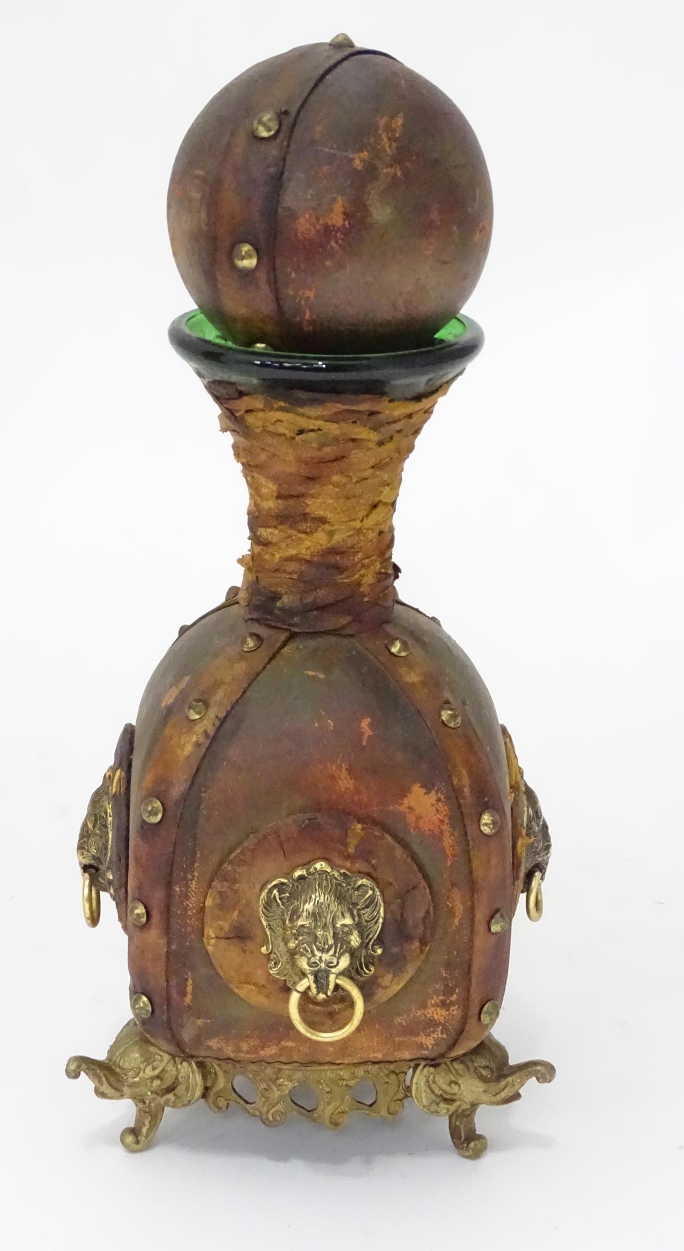 A green glass decanter / carafe with leather wrap cover with stud detail and and lions mask handle