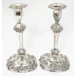 A pair of silver plate candlesticks with acanthus scroll decoration. 10" high overall. Please Note -