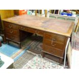 Large early 20thC mahogany desk with leather insert to top and standing on 8 legs with brass casters