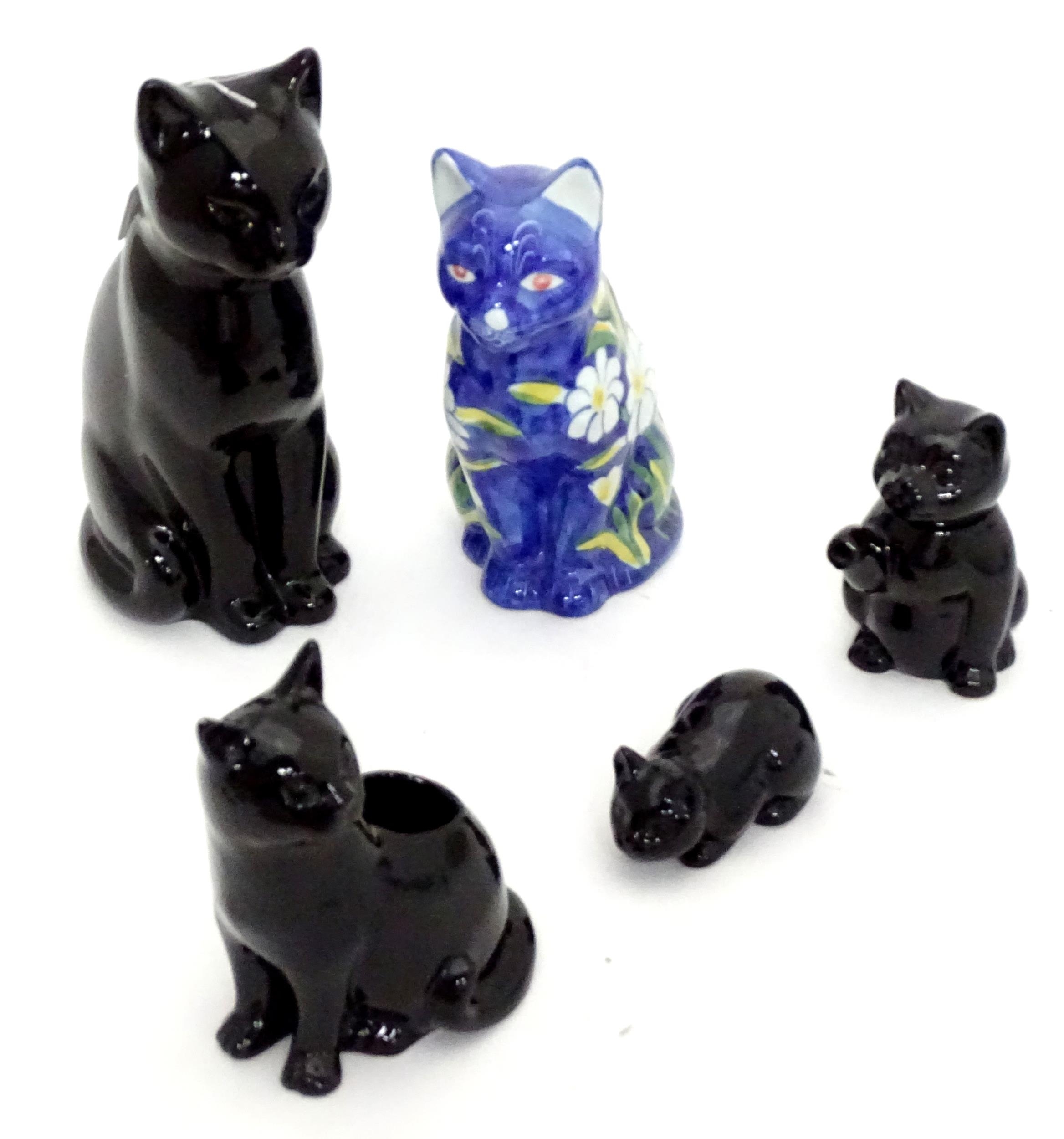 Four ceramic models of cats, together with a small novelty teapot modelled as a black cat. Largest