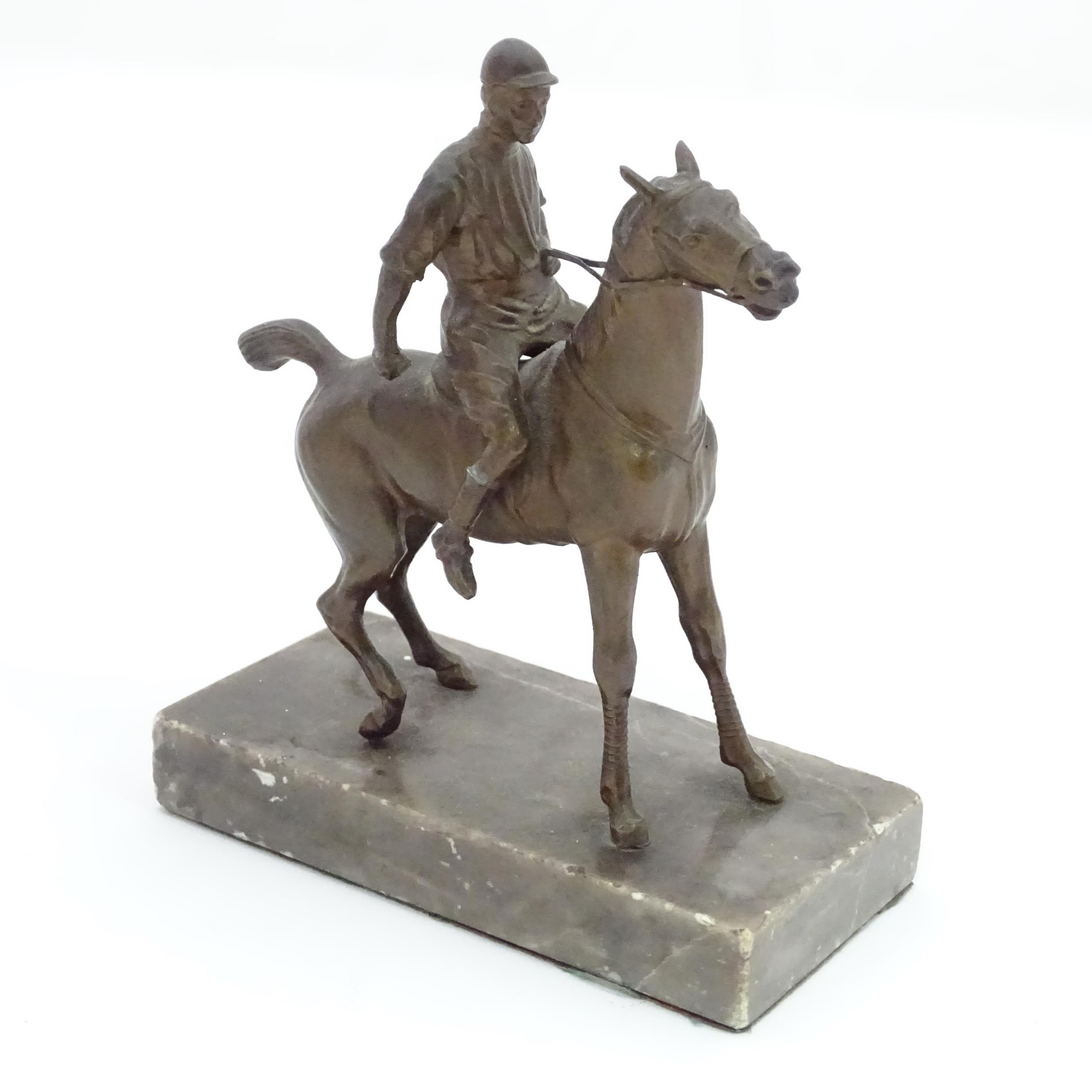 A 20thC cast sculpture modelled as a jockey on horseback, upon a marble base. Approx. 5 1/2" high