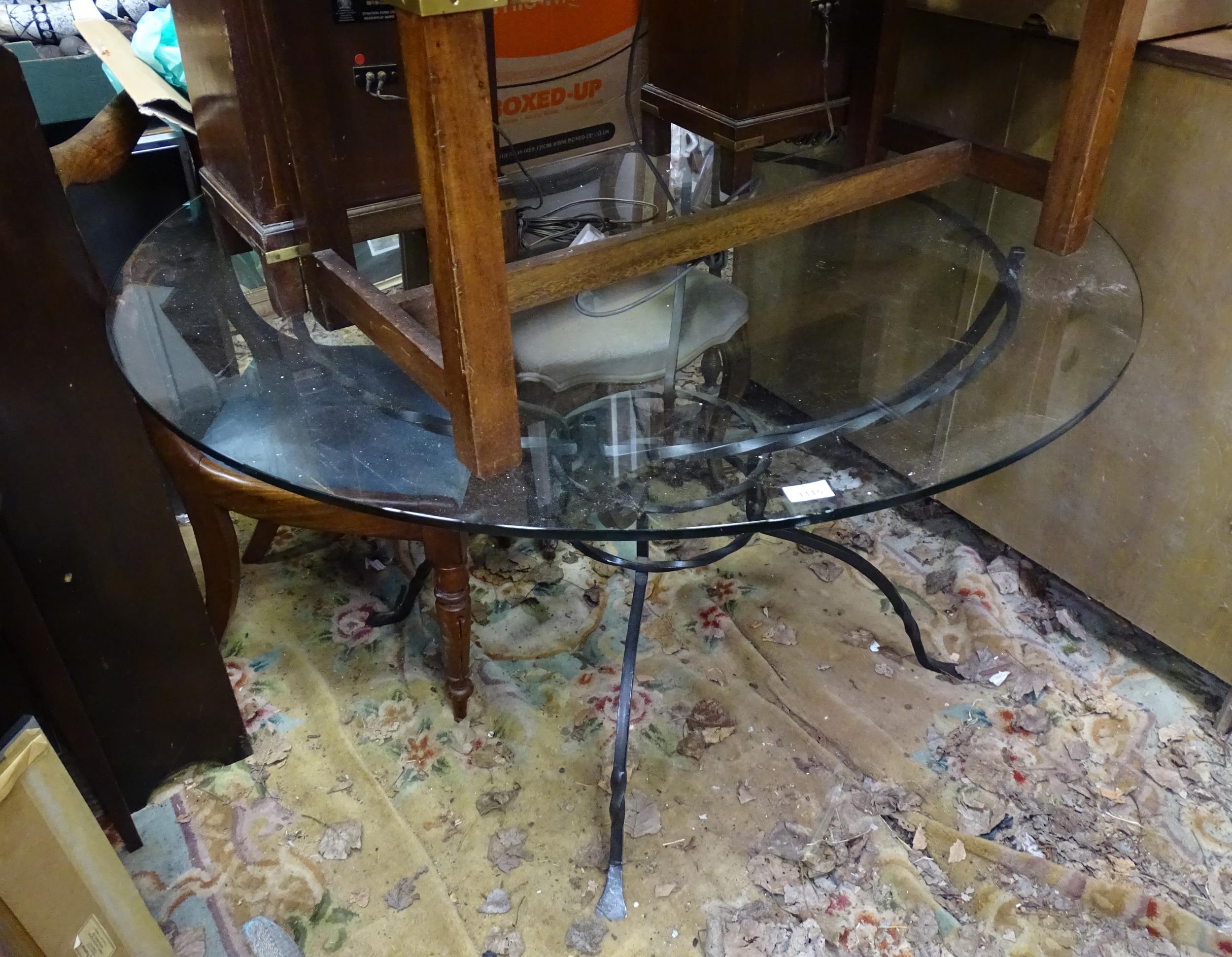 A 20thC circular glass topped dining table with a cast metal base. Approx. 47 1/2" diameter x 29"