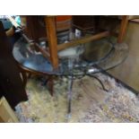 A 20thC circular glass topped dining table with a cast metal base. Approx. 47 1/2" diameter x 29"