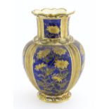 A Brownhills Pottery baluster vase with a blue glaze with gilt daisy flower decoration. Inscribed