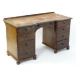 A Victorian pine pedestal desk with a shaped upstand and two banks of four short drawers with a