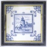 A framed blue and white Delft style tile decorated with figures rowing on a river with buildings