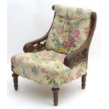A late 19thC Aesthetic movement nursing chair with a scrolled upholstered back and seat flanked by