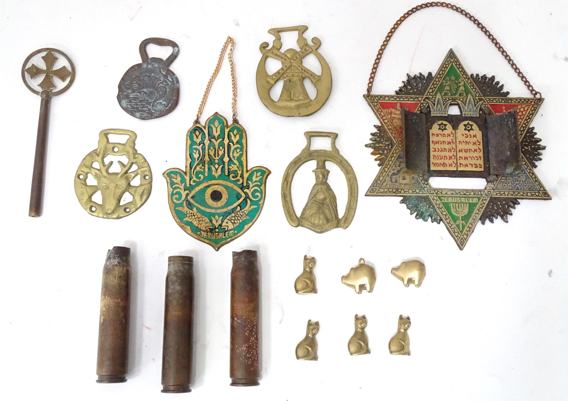 A box of assorted brass items to include a bottle opener, horse brasses, a Hamsa hand with enamel