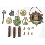 A box of assorted brass items to include a bottle opener, horse brasses, a Hamsa hand with enamel