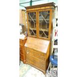 A modern walnut bureau bookcase with glazed doors and a fall front writing slope above four drawers.