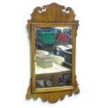 A modern mahogany mirror with carved scrolling mount. Approx. 29" long x 16 3/4" wide Please