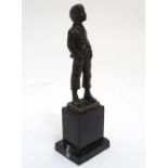 A 20thC bronze sculpture modelled as a young boy whistling with his hands in his pockets, on a